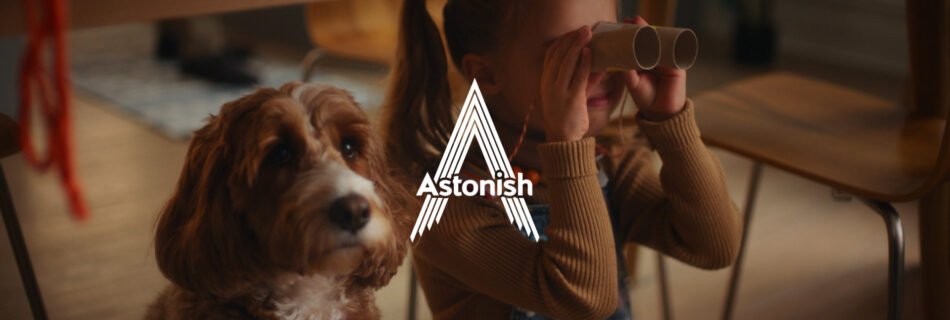 A child with cardboard binoculars, next to a friendly looking dog in an advert for Astonish cleaning products.